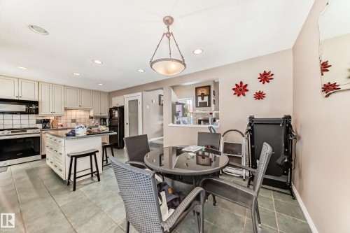 The kitchen features light-colored cabinetry, a center island with a countertop, and stainless steel appliances including an oven and range hood - 597 Millbourne Road E, Edmonton, AB - Indoor