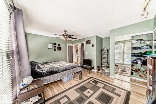 This room features light green walls, light wood flooring, and a ceiling fan - 597 Millbourne Road E, Edmonton, AB - Indoor Photo Showing Bedroom