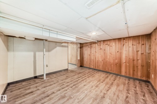 This room features wood paneling on one wall and wood-style flooring - 597 Millbourne Road E, Edmonton, AB - Indoor Photo Showing Basement