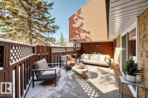 The property features an outdoor patio area with a wooden privacy fence, a sliding glass door, and exterior lighting - 597 Millbourne Road E, Edmonton, AB - Outdoor With Deck Patio Veranda With Exterior