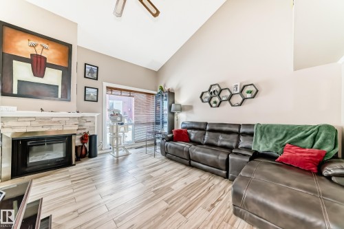 The living room features vaulted ceilings, a stone-faced fireplace, and light-toned flooring - 597 Millbourne Road E, Edmonton, AB - Indoor Photo Showing Living Room With Fireplace