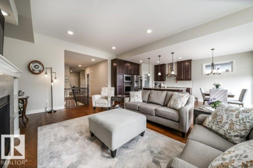 Living area featuring hardwood floors, recessed lighting, and a fireplace with a light-colored mantel - 3 8050 Orchards Green, Edmonton, AB - Indoor Photo Showing Living Room With Fireplace