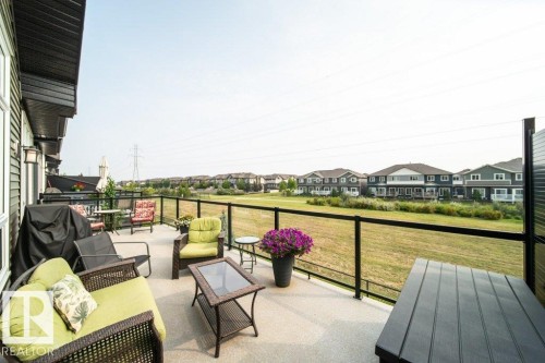 The property features a spacious outdoor deck with a glass railing, providing an open view of the surrounding landscape - 3 8050 Orchards Green, Edmonton, AB - Outdoor With Deck Patio Veranda