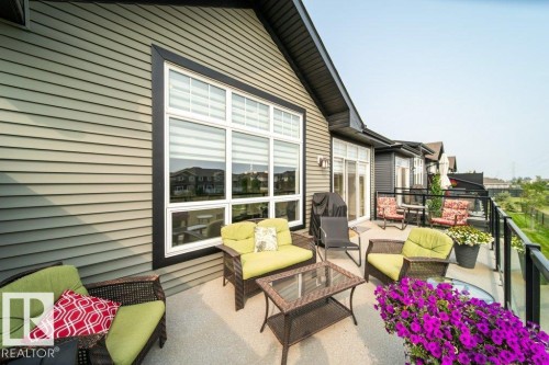Spacious outdoor patio with a glass railing, offering views of the surrounding area - 3 8050 Orchards Green, Edmonton, AB - Outdoor With Deck Patio Veranda With Exterior
