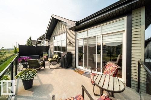 The property features a spacious deck with a glass railing, providing an open view of the surrounding landscape - 3 8050 Orchards Green, Edmonton, AB - Outdoor With Deck Patio Veranda