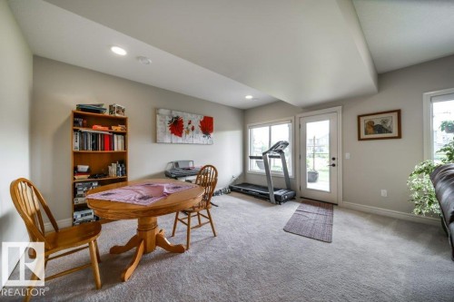 Spacious room featuring light grey carpet, recessed lighting, and a white door with clear glass leading to the exterior - 3 8050 Orchards Green, Edmonton, AB - Indoor