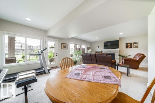 The living area features a light-colored carpet, recessed lighting, and large windows providing natural light - 3 8050 Orchards Green, Edmonton, AB - Indoor
