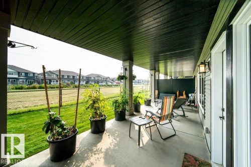 The property features a covered patio with a concrete surface, providing an ideal outdoor living space - 3 8050 Orchards Green, Edmonton, AB - Outdoor With Deck Patio Veranda With Exterior