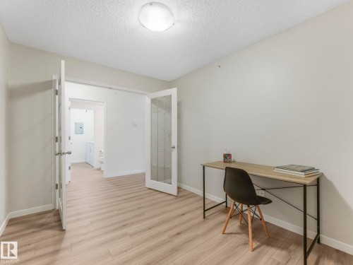 This room features light wood-look flooring, freshly-painted walls, and french doors - 515 10311 111 Street, Edmonton, AB - Indoor
