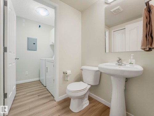Bathroom with a pedestal sink, a toilet, and light wood-style flooring - 515 10311 111 Street, Edmonton, AB - Indoor Photo Showing Bathroom