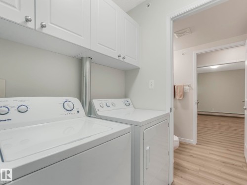 The property includes a laundry area with white appliances and wall-mounted white cabinetry, offering practical storage solutions - 515 10311 111 Street, Edmonton, AB - Indoor Photo Showing Laundry Room