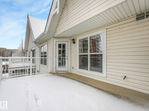 The property features a private balcony with views of Grant MacEwen University, white railings, a white exterior, and a glass door from the living room. - 515 10311 111 Street, Edmonton, AB - Outdoor With Deck Patio Veranda With Exterior