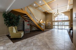 The property features a spacious lobby with a grand wooden staircase, tiled flooring, and an elegant chandelier - 