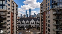 Modern high-rise residential building with balconies featuring glass railings and a cityscape backdrop - 