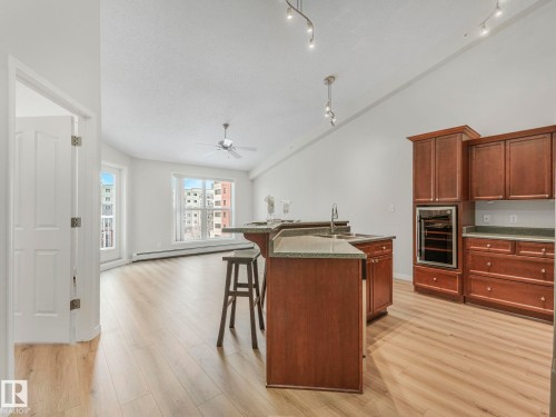 Open concept living space featuring light wood-style flooring, a kitchen island with seating, a built-in oven, and track lighting - 515 10311 111 Street, Edmonton, AB - Indoor