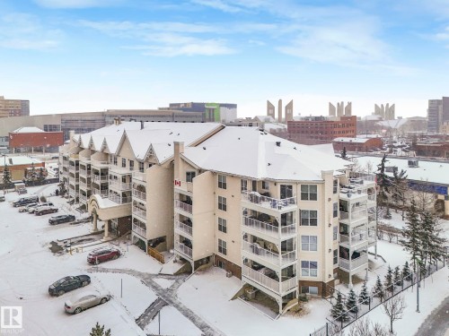 This property features a multi-story building with a light-colored exterior and a snow-covered roof - 515 10311 111 Street, Edmonton, AB - Outdoor With View