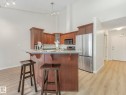 Kitchen featuring wood cabinetry, stainless steel appliances, a bar-height counter, and track lighting - 515 10311 111 Street, Edmonton, AB  - Indoor Photo Showing Kitchen With Upgraded Kitchen 