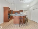 The kitchen features rich wood cabinetry, stainless steel appliances, and a breakfast bar - 515 10311 111 Street, Edmonton, AB  - Indoor Photo Showing Kitchen 