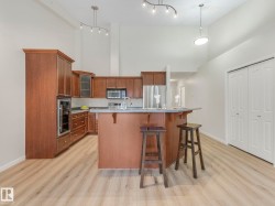 The kitchen features rich wood cabinetry, stainless steel appliances, and a breakfast bar - 