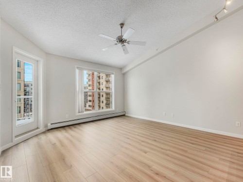This living space features new light-toned flooring, a ceiling fan, and track lighting - 515 10311 111 Street, Edmonton, AB - Indoor Photo Showing Other Room