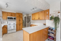 Kitchen featuring brick wall, rail lighting, white appliances, light countertops - 