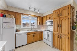 Kitchen with white appliances, brown cabinetry, and light countertops - 