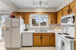 Kitchen with white appliances, brown cabinetry, and light countertops - 