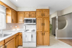 Kitchen featuring electric stove, brown cabinets, light countertops, and light tile patterned floors - 