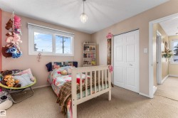 Bedroom with a closet, a textured ceiling, light carpet, and multiple windows - 