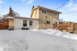Snow covered house featuring a wooden deck and stucco siding - 