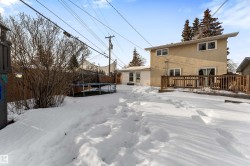 Snow covered property with a trampoline and stucco siding - 