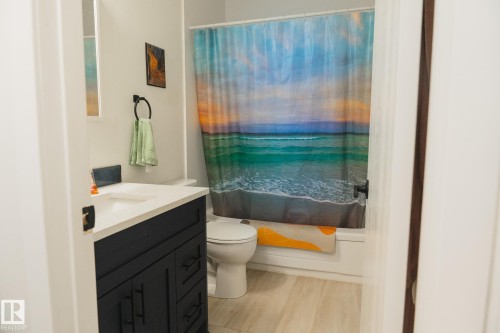 This bathroom features a contemporary dark vanity with a white countertop and a white toilet - 303 10432 76 Avenue, Edmonton, AB - Indoor Photo Showing Bathroom