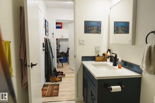 Bathroom featuring a vanity with a white countertop and a dark blue base cabinet, a wall-mounted mirror, and a black faucet - 303 10432 76 Avenue, Edmonton, AB - Indoor Photo Showing Bathroom