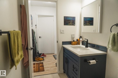 Bathroom featuring a vanity with a white countertop and a dark blue cabinet, a rectangular mirror, and a black faucet - 303 10432 76 Avenue, Edmonton, AB - Indoor Photo Showing Bathroom