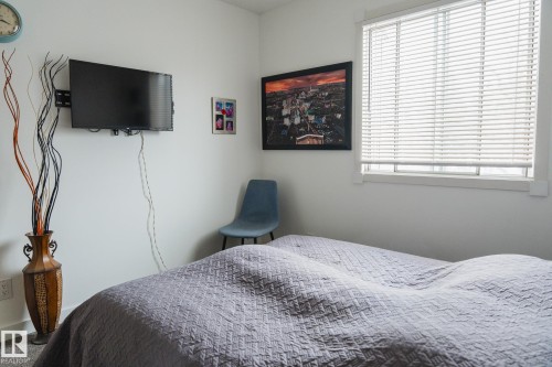 This room features a window with blinds, light-colored walls, and a mounted television - 303 10432 76 Avenue, Edmonton, AB - Indoor Photo Showing Bedroom