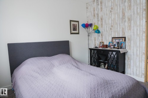 This interior space features white walls and a distinct accent wall with a light-toned, vertically oriented wood panel design - 303 10432 76 Avenue, Edmonton, AB - Indoor Photo Showing Bedroom