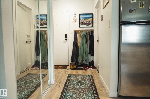 The entryway features light-toned flooring, a mirrored closet door, and a stainless steel refrigerator - 303 10432 76 Avenue, Edmonton, AB - Indoor Photo Showing Other Room