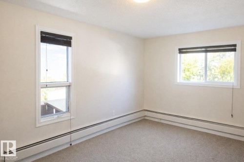 Carpeted empty room featuring a baseboard radiator and a textured ceiling - 10831 80 Avenue, Edmonton, AB - Indoor Photo Showing Other Room