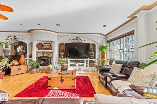 This living space features hardwood floors and a built-in entertainment center with a fireplace and shelving - 11124 110A Avenue, Edmonton, AB - Indoor Photo Showing Living Room With Fireplace