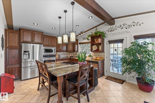 The kitchen features extensive wood cabinetry, stainless steel appliances, a large island with a granite countertop, and recessed lighting - 11124 110A Avenue, Edmonton, AB - Indoor