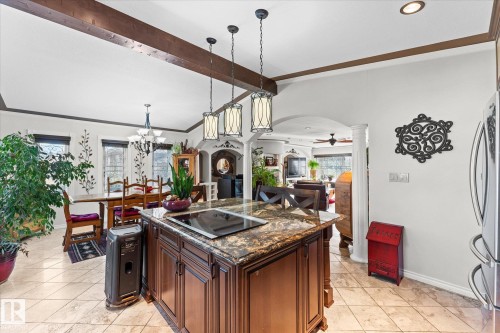 The kitchen features a dark wood island with a granite countertop and an integrated cooktop, illuminated by three pendant lights - 11124 110A Avenue, Edmonton, AB - Indoor Photo Showing Kitchen