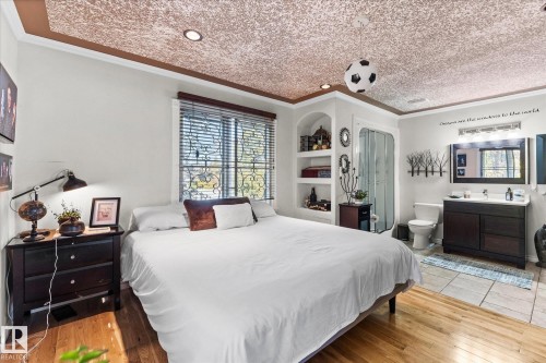 This room features hardwood floors in the sleeping area and tiled flooring in the vanity area - 11124 110A Avenue, Edmonton, AB - Indoor Photo Showing Bedroom