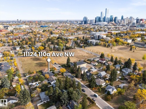 The property is situated in a neighborhood with extensive greenery, featuring mature trees and open grassy areas, and offers views of the city skyline - 11124 110A Avenue, Edmonton, AB - Outdoor With View