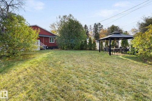 The property features a spacious yard with a lawn, mature trees, and a gazebo with outdoor seating - 11124 110A Avenue, Edmonton, AB - Outdoor