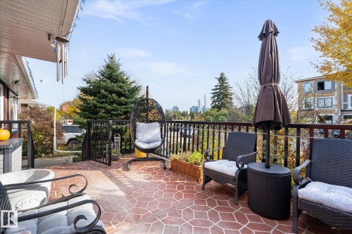 The property features an expansive outdoor patio with a red patterned surface, black metal railings, and views of city buildings in the distance - 11124 110A Avenue, Edmonton, AB - Outdoor With Exterior
