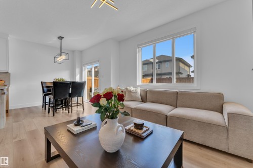 The living area features light hardwood flooring, a large window, and a sliding glass door - 9 Hunter Place, Spruce Grove, AB - Indoor Photo Showing Living Room