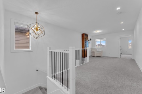 Bright and open upper level space featuring plush grey carpeting, a modern geometric chandelier, and recessed lighting - 9 Hunter Place, Spruce Grove, AB - Indoor Photo Showing Other Room