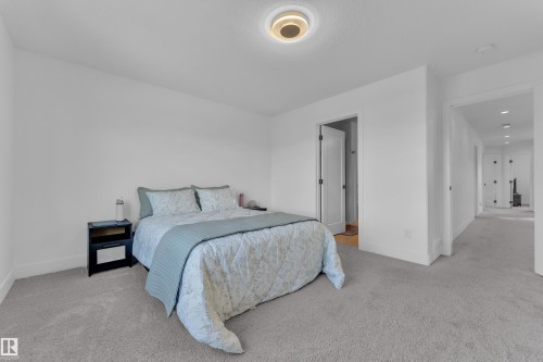 This room features light-colored carpeting, white walls, and a modern ceiling light fixture - 9 Hunter Place, Spruce Grove, AB - Indoor Photo Showing Bedroom