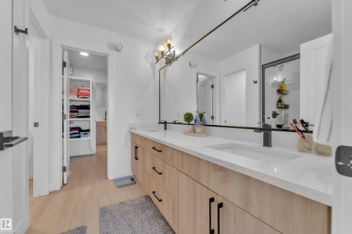The bathroom features a double vanity with light wood cabinetry, a white countertop, and dark-toned faucets - 9 Hunter Place, Spruce Grove, AB - Indoor