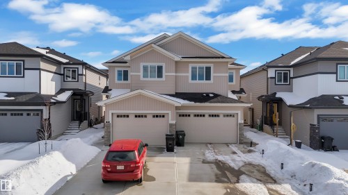 The property features a two-story exterior with light-colored siding, a dark roof, and a two-car attached garage - 9 Hunter Place, Spruce Grove, AB - Outdoor With Facade